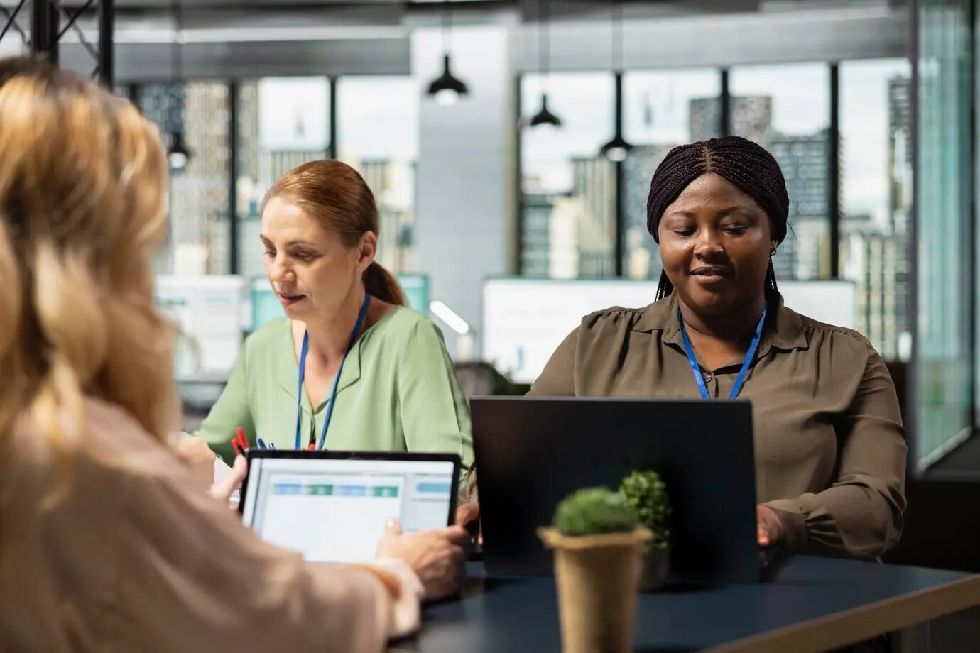 Разнообразная группа офисных коллег изучает бизнес-инсайты на ноутбуке перед постановкой целей в современной обстановке.